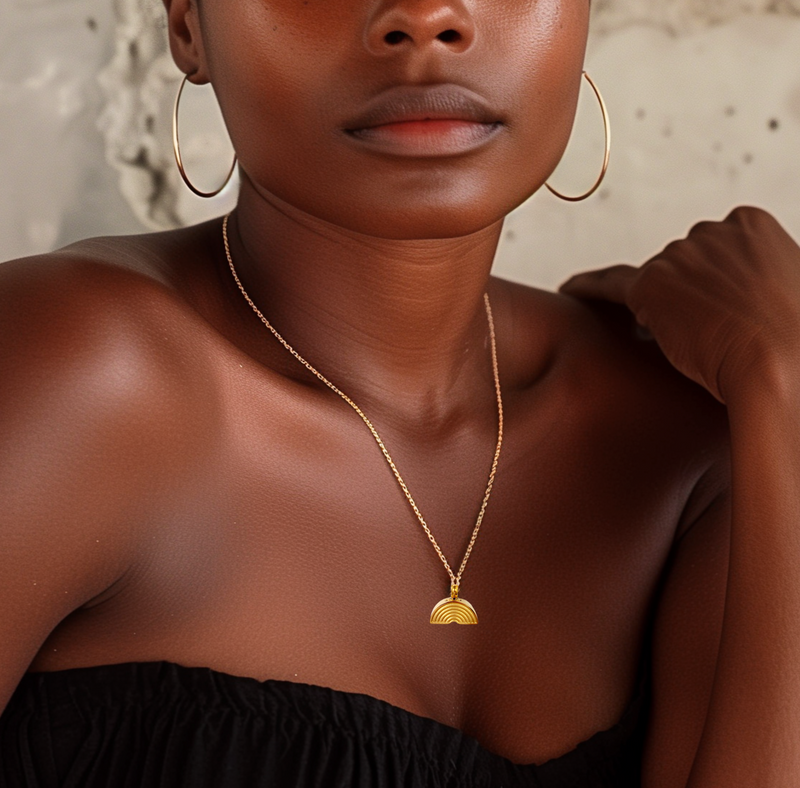 dark skinned woman wearing a dainty, gold, GNight Fetcher cremation necklace shaped like a rainbow
